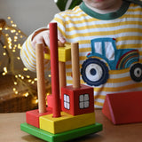 Child placing blocks onto the poles on the base pieces of the Ostheimer multi coloured block house.
