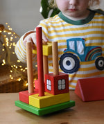 Child placing blocks onto the poles on the base pieces of the Ostheimer multi coloured block house.