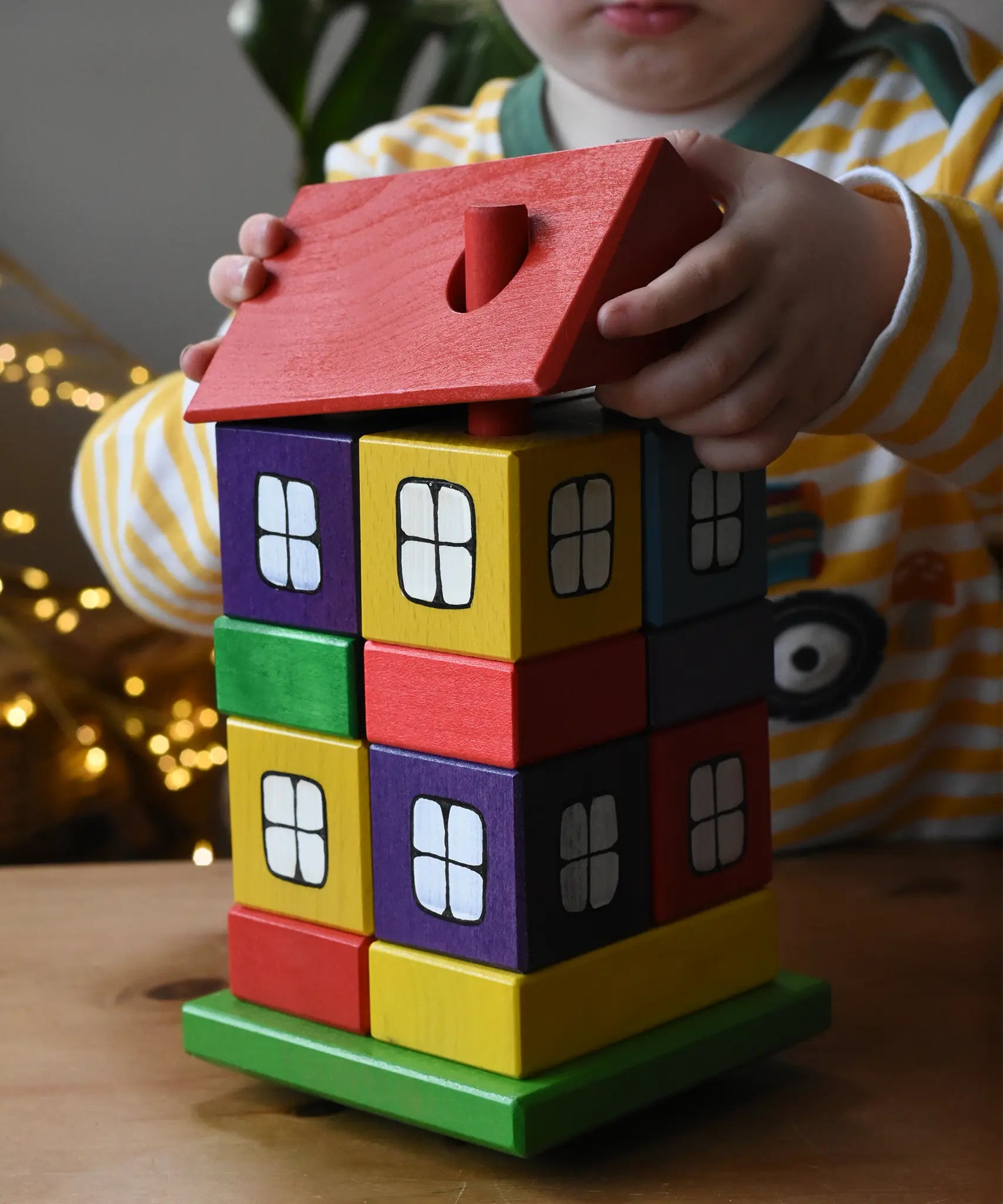 Child lifting the roof off the Ostheimer multi coloured block house.