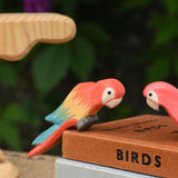 A close up of an Ostheimer multicoloured parrot figure perching on a pile of old books.