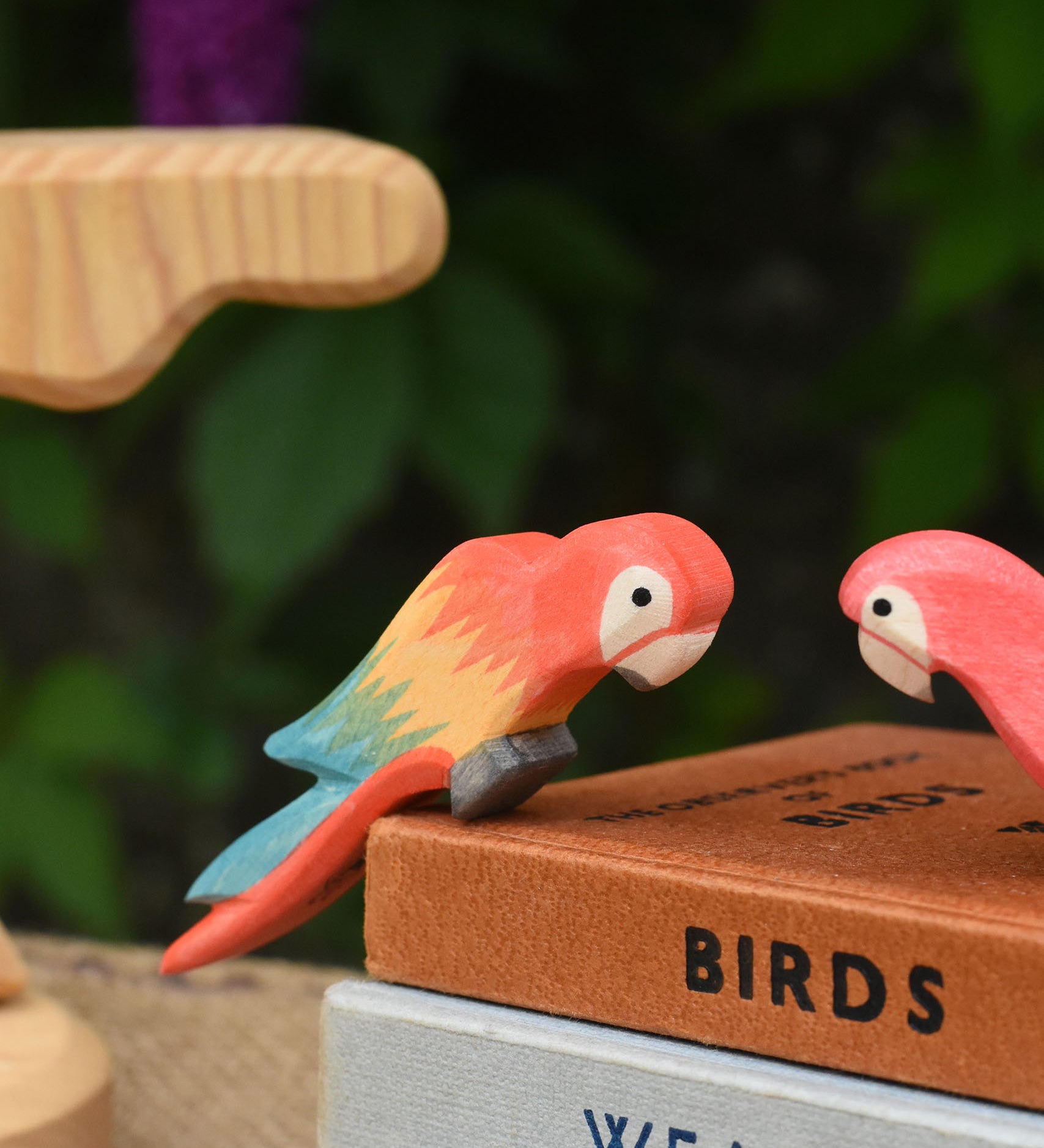 A close up of an Ostheimer multicoloured parrot figure perching on a pile of old books.
