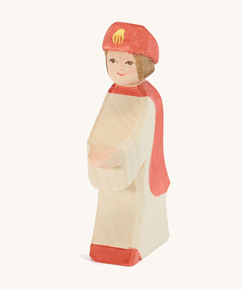 Ostheimer Red King’s Page wooden nativity figure, a Waldorf inspired Star Singer with white skin and brown hair, wearing a white robe with a red cloak and red hat, hand madefrom natural wood