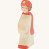 Ostheimer Red King’s Page wooden nativity figure, a Waldorf inspired Star Singer with white skin and brown hair, wearing a white robe with a red cloak and red hat, hand madefrom natural wood