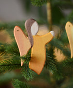 Ostheimer orange angel wooden handmade decoration placed on a Christmas tree branch. 