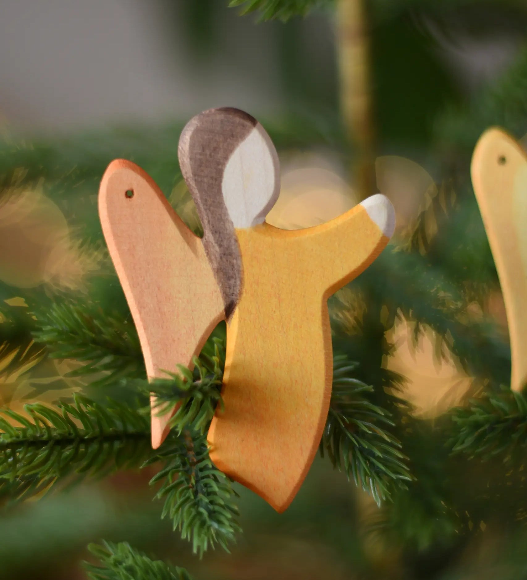 Ostheimer orange angel wooden handmade decoration placed on a Christmas tree branch. 