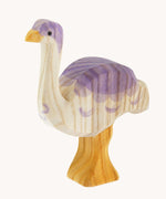 Ostheimer Ostrich wooden toy figure pictured at a slight angle. The photo shows the natural wood grain detail on the handcarfted figure. The ostrich has a white base, light yellow orange legs and beak and purple coloured details.