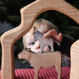 A child placing an Ostheimer small donkey figure on top of an Ostheimer ox figure. These wooden figures are part of a wide range of expertly hand crafted wooden toys here at Babipur. 