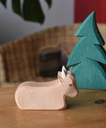 Ostheimer ox wooden toy figure placed on a wooden surface with a small spruce tree.