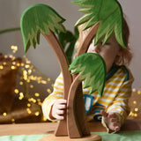 Ostheimer palm tree group with support base placed on a green cotton play cloth with a child standing behind it.