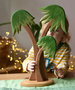 Ostheimer palm tree group with support base placed on a green cotton play cloth with a child standing behind it.
