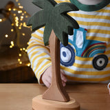 Ostheimer palm tree wooden toy figure with support base placed on a wooden surface.