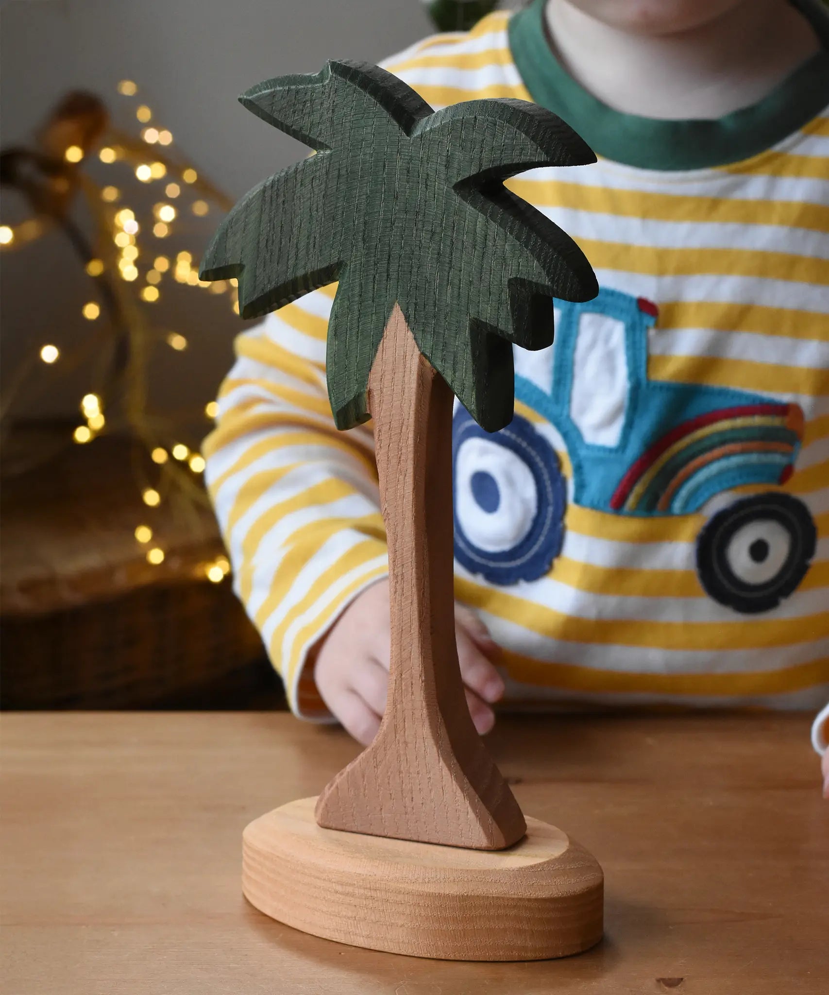 Ostheimer palm tree wooden toy figure with support base placed on a wooden surface.