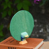 A view of the back of the Ostheimer peacock wooden toy figure with open feathers placed on a pile of books.