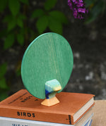 A view of the back of the Ostheimer peacock wooden toy figure with open feathers placed on a pile of books.