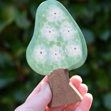 Ostheimer wooden golden pear tree scenery piece shown on the blossom side in an adult's hand. 