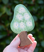 Ostheimer wooden golden pear tree scenery piece shown on the blossom side in an adult's hand. 