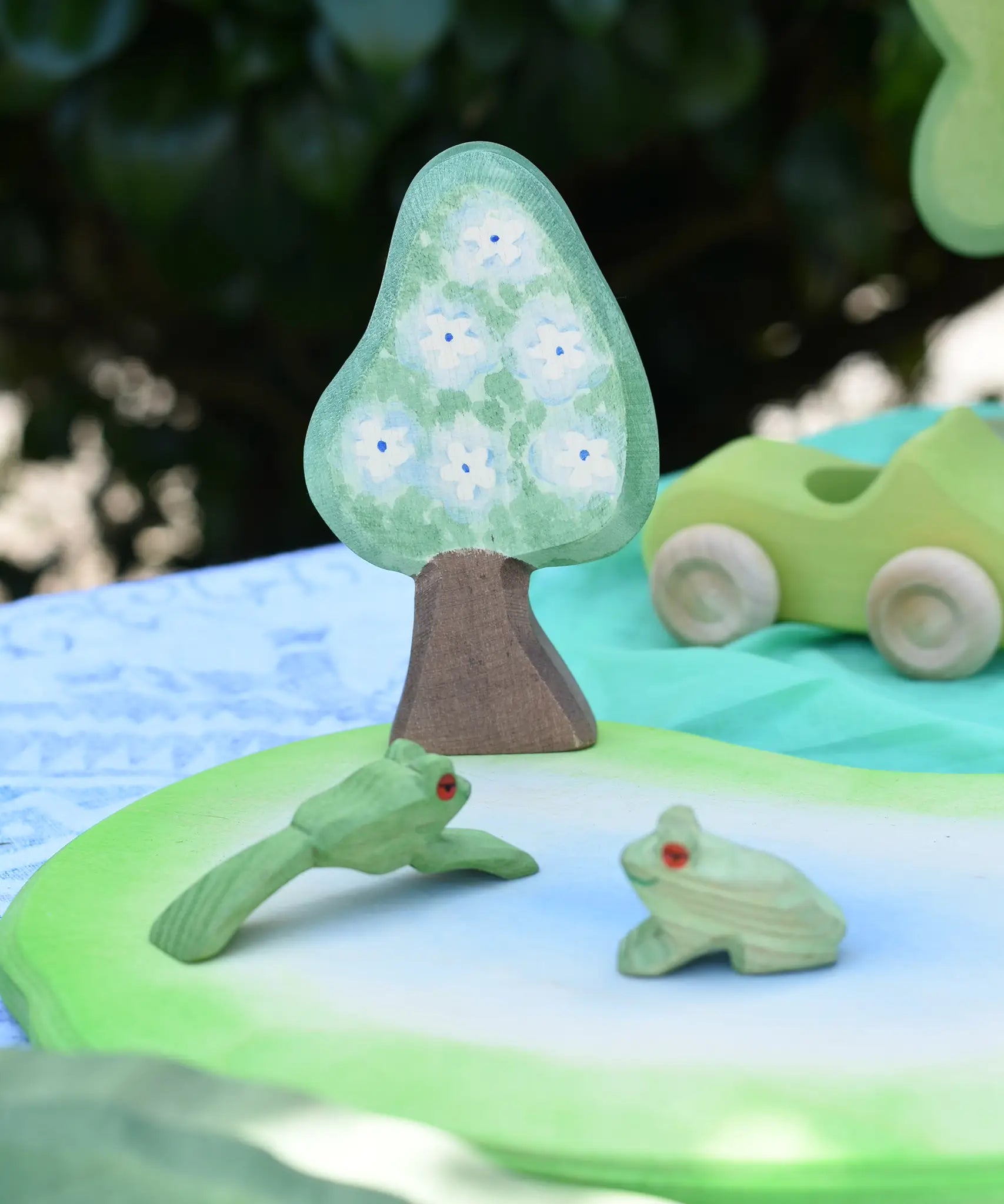 Ostheimer wooden golden pear tree shown on the blue flower side scenery piece used in a small world play set up with a pond piece and frogs. 