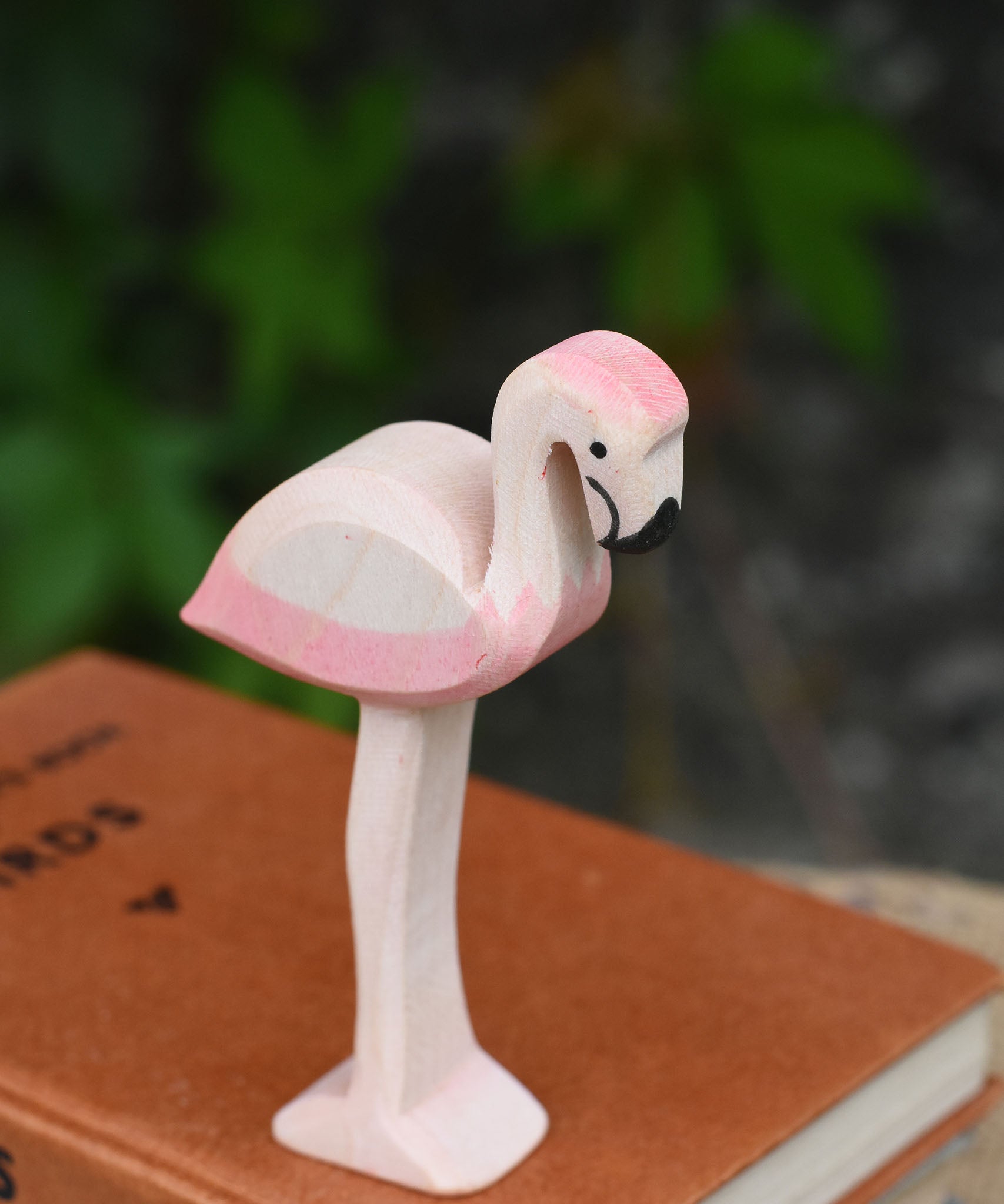 A close up of an Ostheimer flamingo placed on a pile of books.