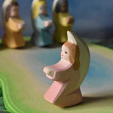 A pink coloured Ostheimer little angel placed on an Ostheimer pond piece in a small world play set up. This wooden figure is part of a large range of expertly hand crafted, Waldorf inspired, wooden toys here at Babipur. 