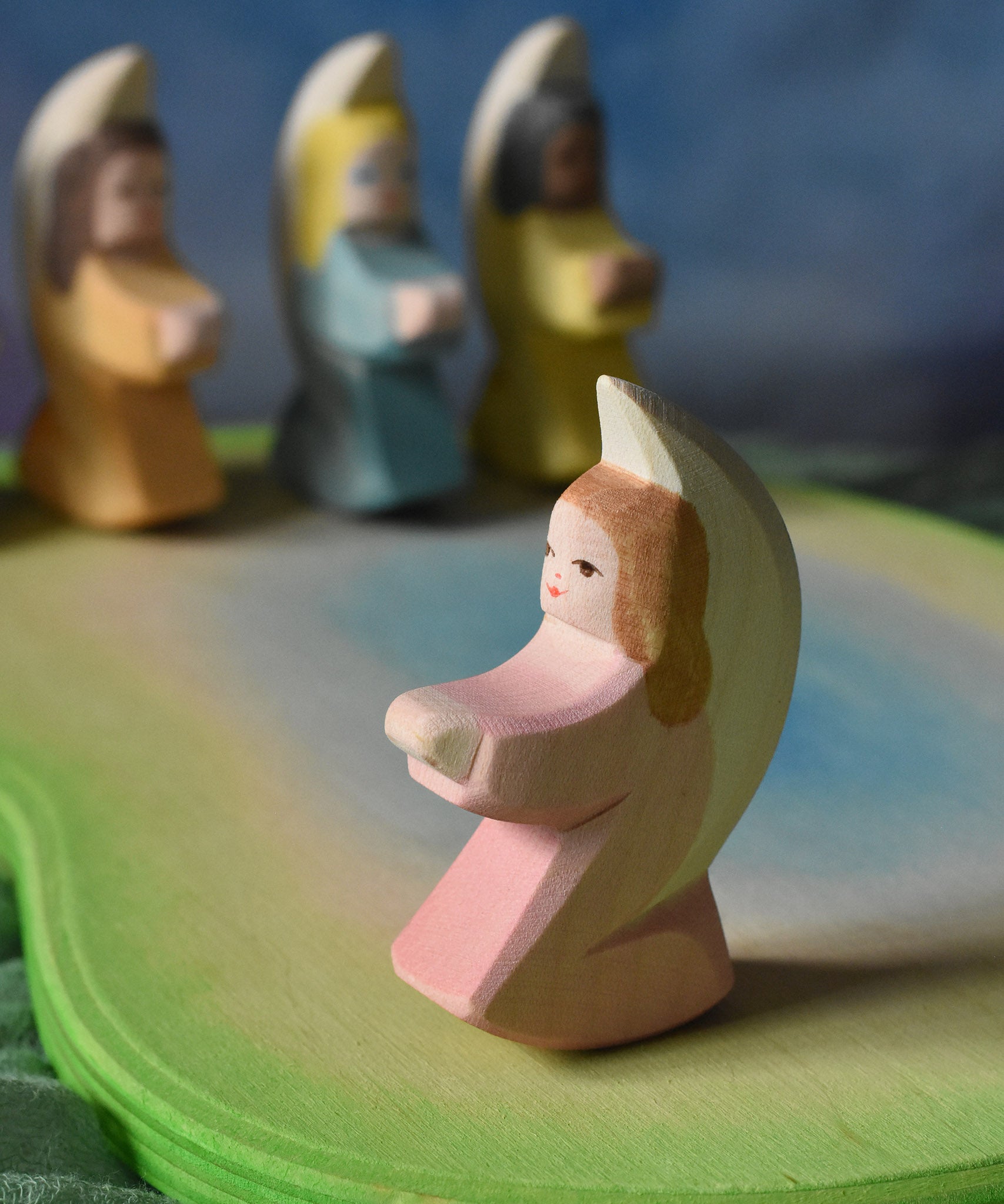 A pink coloured Ostheimer little angel placed on an Ostheimer pond piece in a small world play set up. This wooden figure is part of a large range of expertly hand crafted, Waldorf inspired, wooden toys here at Babipur. 