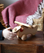 Child twirling the propellor on teh front of the Ostheimer Natural Open Plane With 1 red Person doll placed inside.