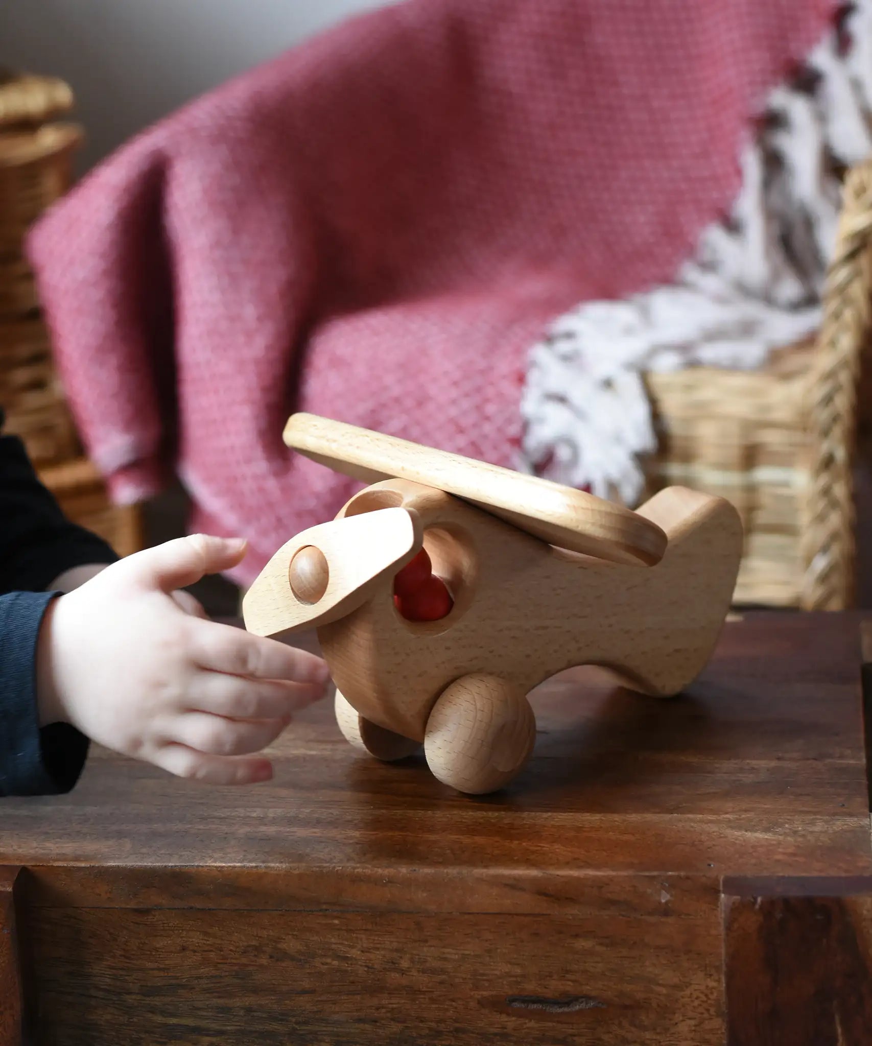 Child twirling the propellor on teh front of the Ostheimer Natural Open Plane With 1 red Person doll placed inside.