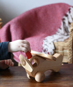 Close up of a child's hand placing teh red people doll inside the Ostheimer Natural Open Plane.
