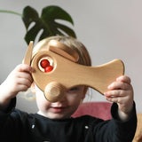 Child holding up the Ostheimer Natural Open Plane With 1 red Person doll placed inside.