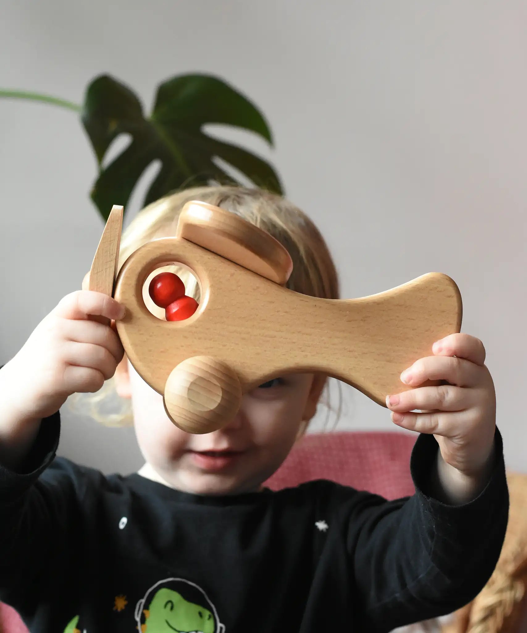 Child holding up the Ostheimer Natural Open Plane With 1 red Person doll placed inside.