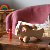 Ostheimer Natural Open Plane With 1 red Person doll placed on a wooden stool.
