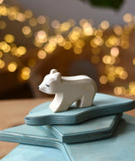 Ostheimer polar bear wooden toy figure with a short neck placed on a stack of ice floe scenery pieces. 