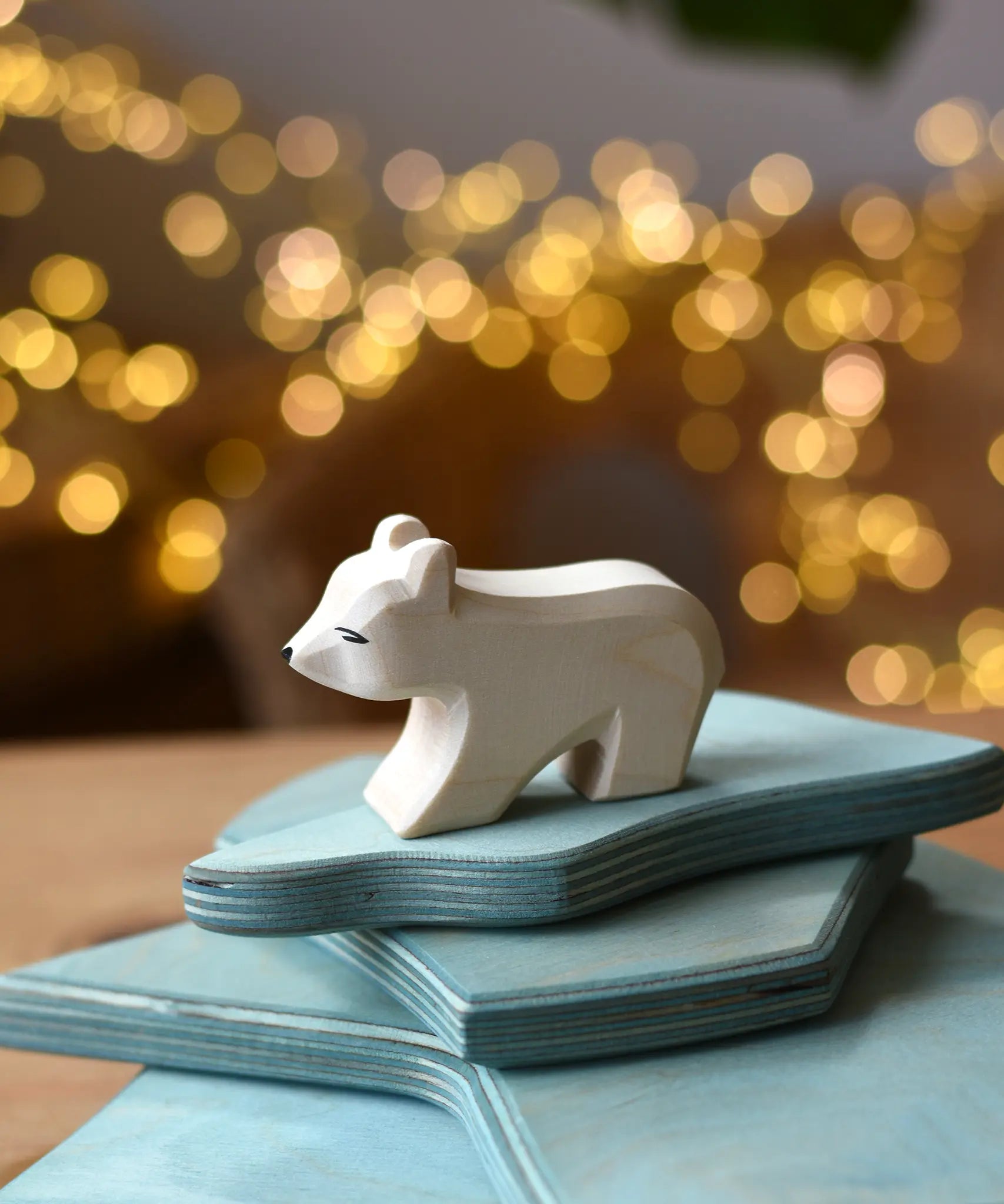 Ostheimer polar bear wooden toy figure with a short neck placed on a stack of ice floe scenery pieces. 