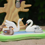 An Ostheimer wooden pond placed in the centre of a small world play scene with Ostheimer duck and swan figures. An Ostheimer bird tree can be seen in the background. 