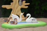 An Ostheimer wooden pond placed in the centre of a small world play scene with Ostheimer duck and swan figures. An Ostheimer bird tree can be seen in the background. 