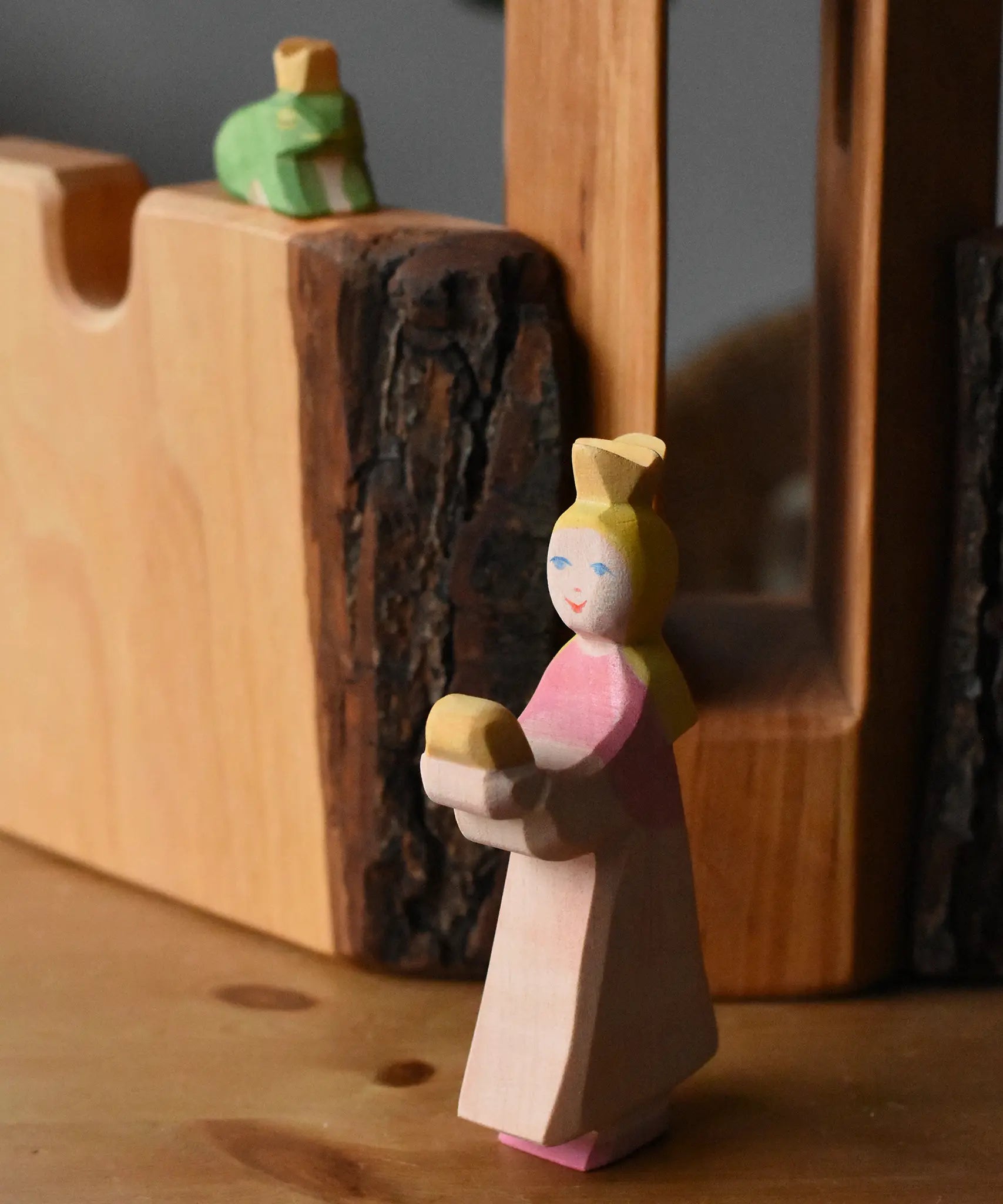 Ostheimer princess for frog king on a wooden surface in front of the tower and castle walls with the frog king in the background.