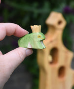 An Ostheimer wooden frog price wooden toy figure shown in an adult's finger's for scale. This wooden figure is part of a large range of expertly hand crafted wooden toys here at Babipur. 