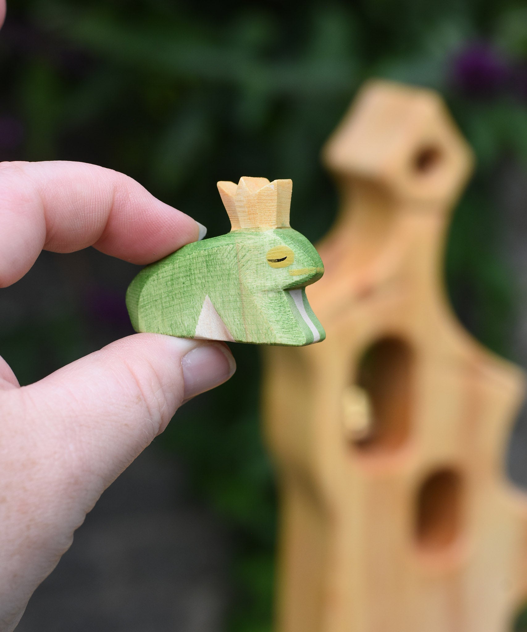 An Ostheimer wooden frog price wooden toy figure shown in an adult's finger's for scale. This wooden figure is part of a large range of expertly hand crafted wooden toys here at Babipur. 