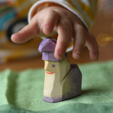 Child's hand reaching for the Ostheimer amethyst dwarf wooden toy figure .