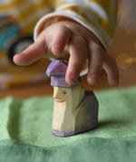 Child's hand reaching for the Ostheimer amethyst dwarf wooden toy figure .