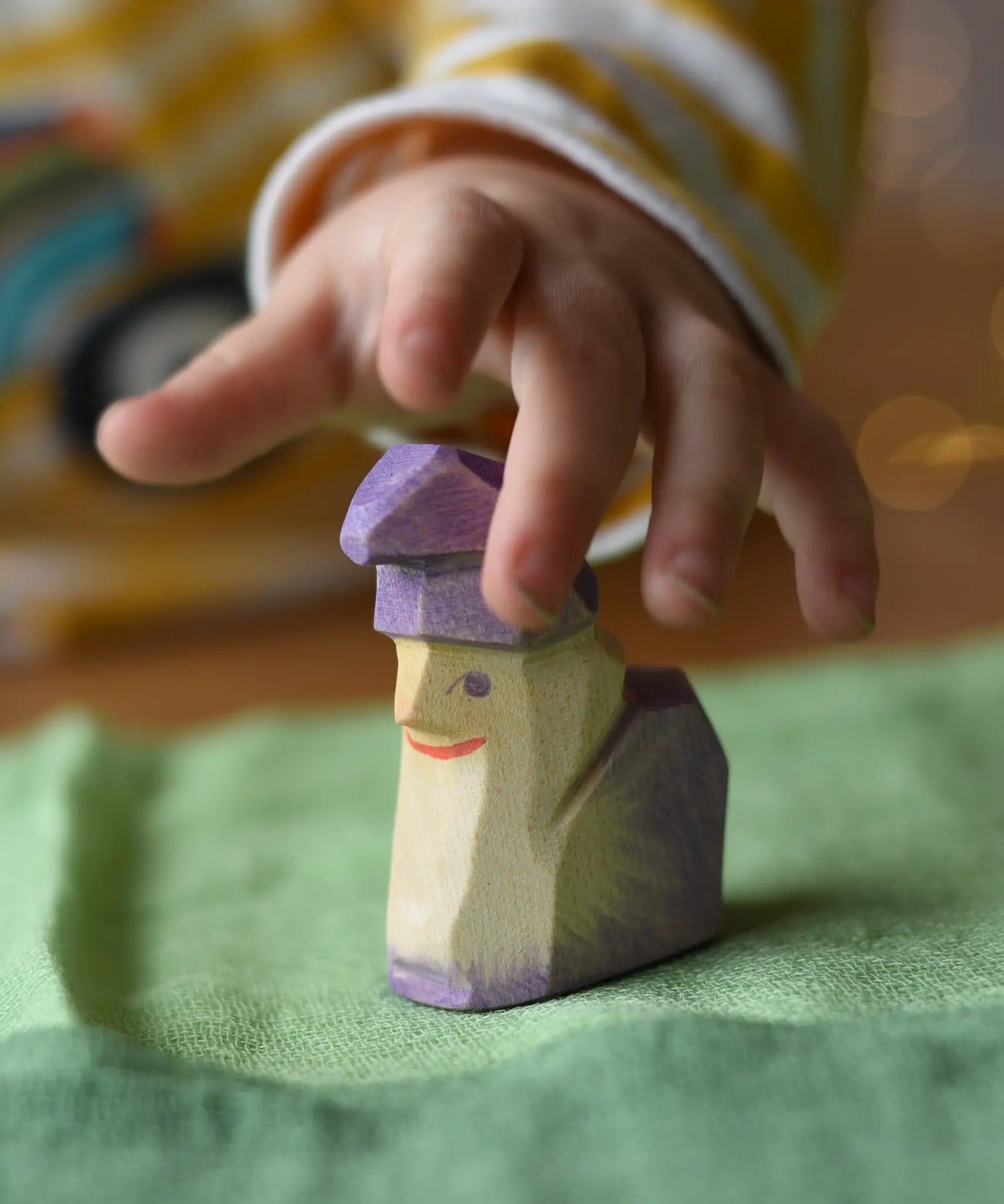 Child's hand reaching for the Ostheimer amethyst dwarf wooden toy figure .