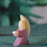 A purple coloured little Ostheimer angel placed on a green decoration scarf. This wooden figure is part of a large range of expertly hand crafted, Waldorf inspired, wooden toys here at Babipur.