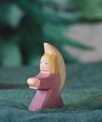 A purple coloured little Ostheimer angel placed on a green decoration scarf. This wooden figure is part of a large range of expertly hand crafted, Waldorf inspired, wooden toys here at Babipur.