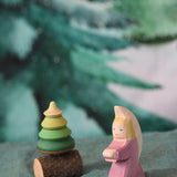 A purple coloured Ostheimer little angel placed on a green coloured decoration scarf next to a Mader spinner. This wooden figure is part of a large range of expertly hand crafted, Waldorf inspired, wooden toys here at Babipur.
