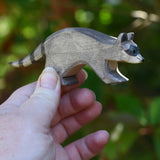 An Ostheimer running raccoon wooden toy figure held in an adult's hand to show scale. Check out our full range of expertly crafted wooden toy figures and scenery here at Babipur.
