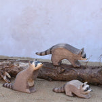 Three Ostheimer wooden toy raccoon figures placed in a simple small world play scene. Check out our full range of expertly crafted wooden toy figures and scenery here at Babipur.