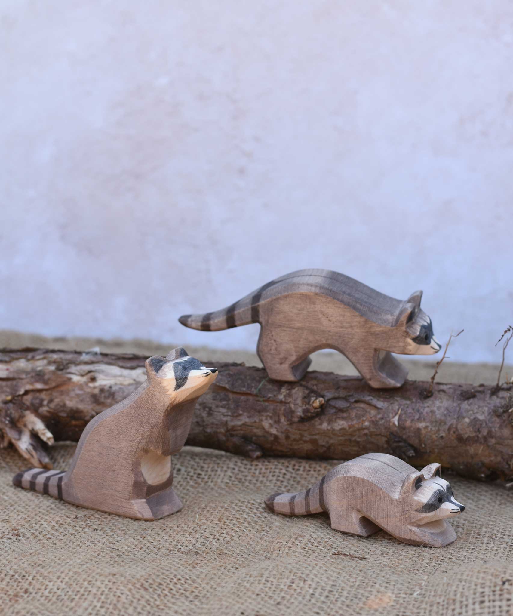 Three Ostheimer wooden toy raccoon figures placed in a simple small world play scene. Check out our full range of expertly crafted wooden toy figures and scenery here at Babipur.