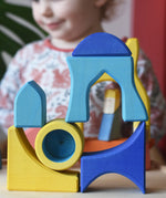 Yellow and blue Ostheimer Rainbow Castle Blocks stacked and balanced on each other.
