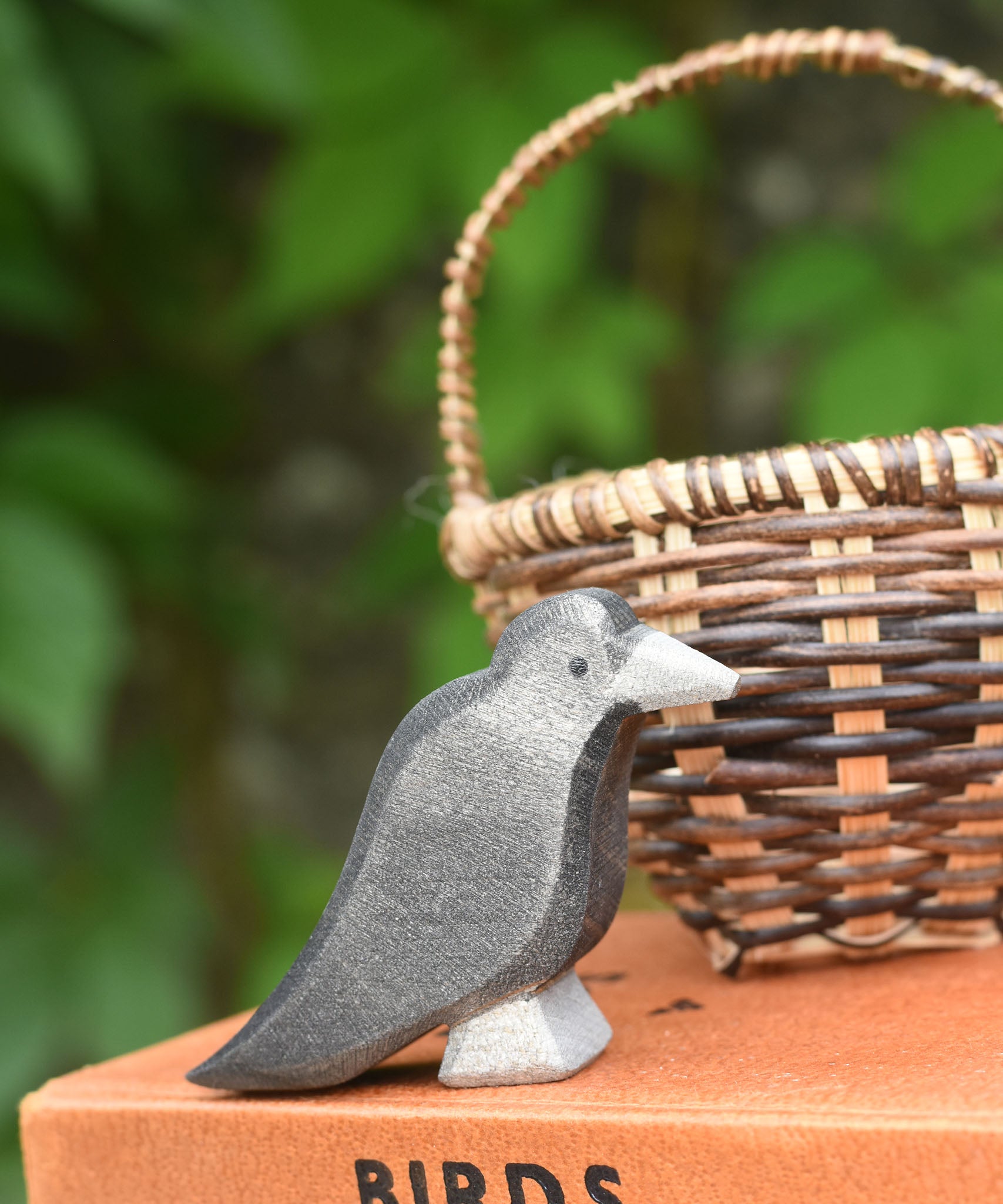 A raven bird figure placed on a pile of old books. 