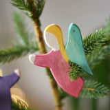 Ostheimer red angel wooden handmade decoration placed on a Christmas tree branch. 