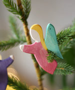 Ostheimer red angel wooden handmade decoration placed on a Christmas tree branch. 